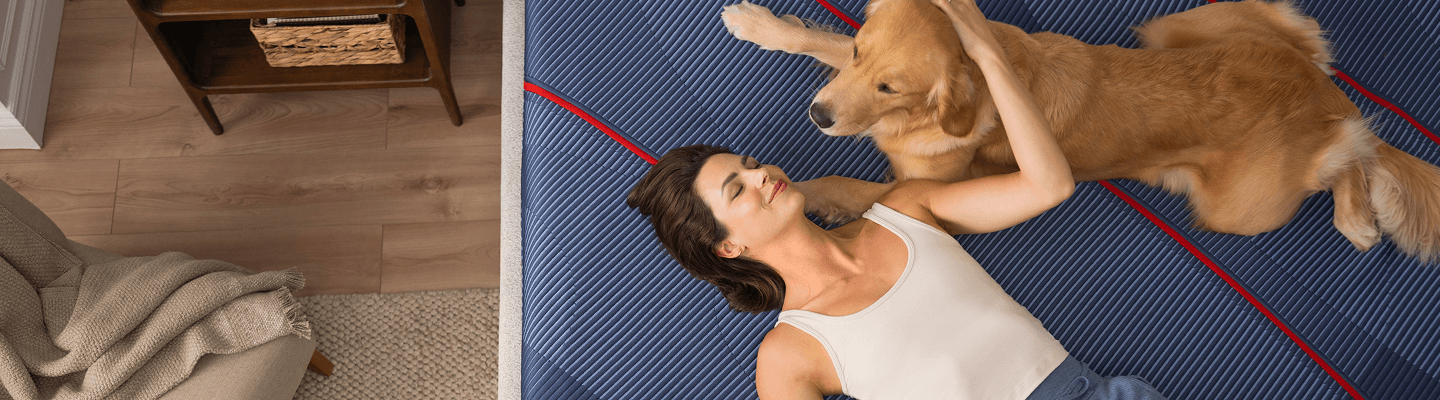 a woman with her golden retreiver relaxing on an Elite mattress model