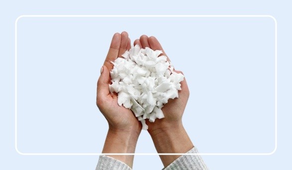 Two hands holding shredded Sealy blend memory foam with a rounded white border