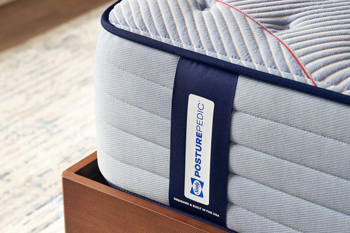A closeup of the corner of a Posturepedic Spring Tight Top mattress in a styled room