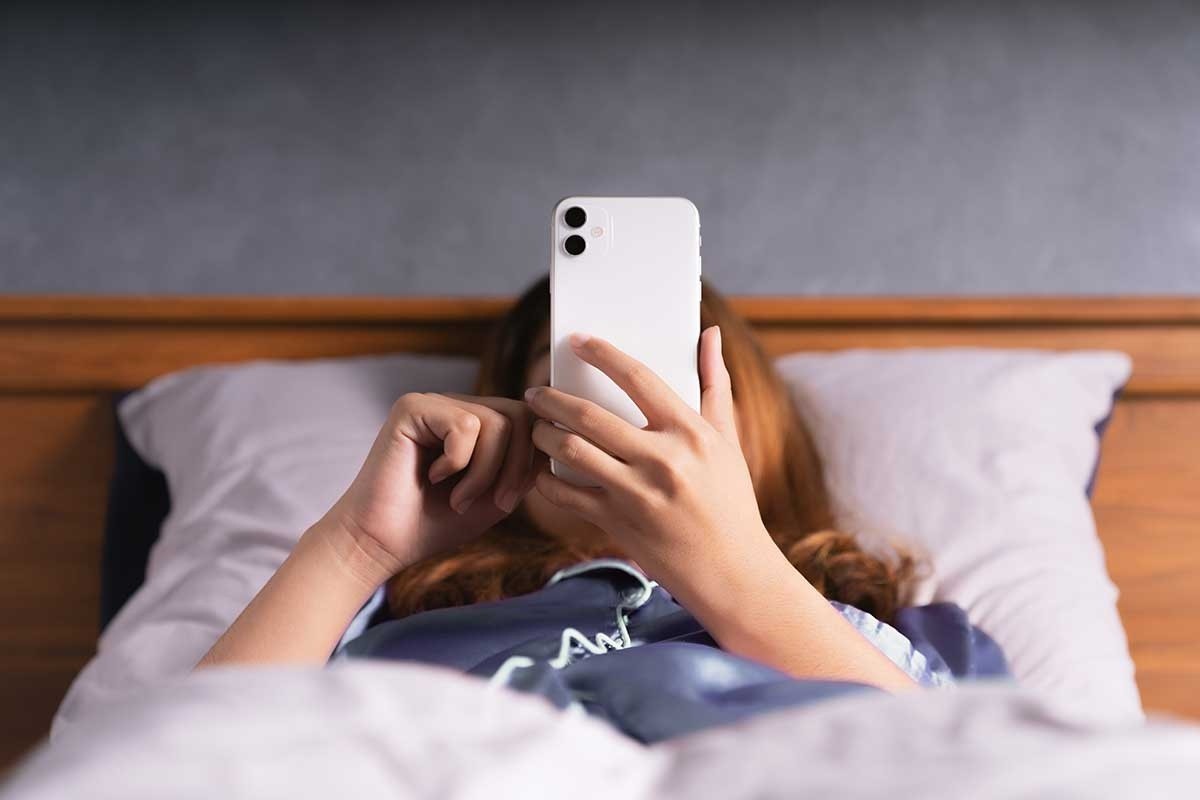 Woman scrolling on her phone while in bed